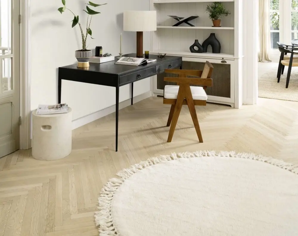 Tapis rond à franges sur un parquet en chevrons, bureau en bois noir